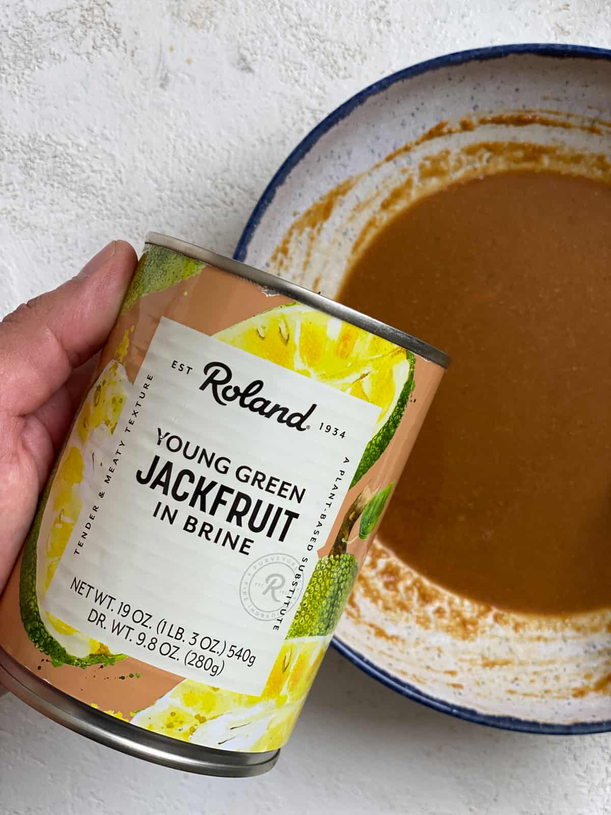 can of jackfruit alongside bowl of sauce
