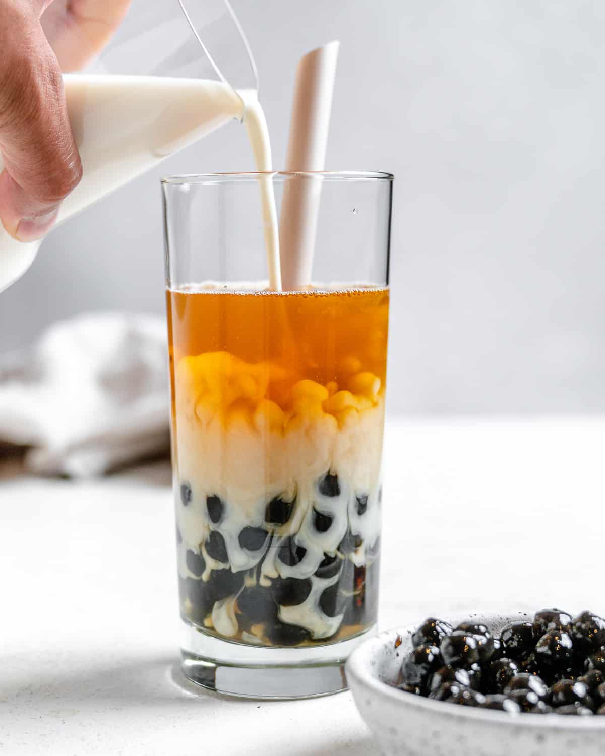 process shot of pouring creamer into glass against a light background