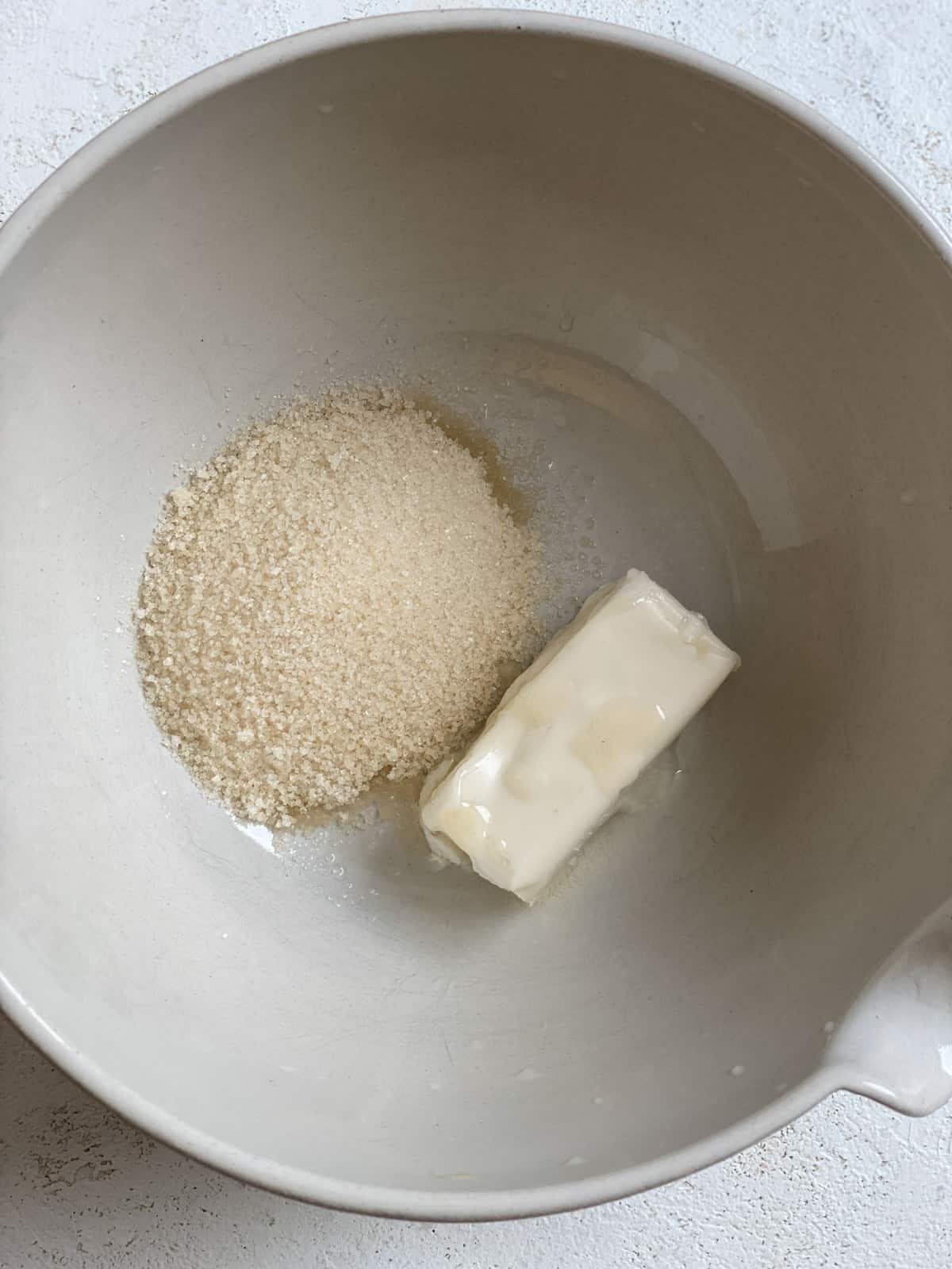 process of mixing sugar and butter in a white bowl