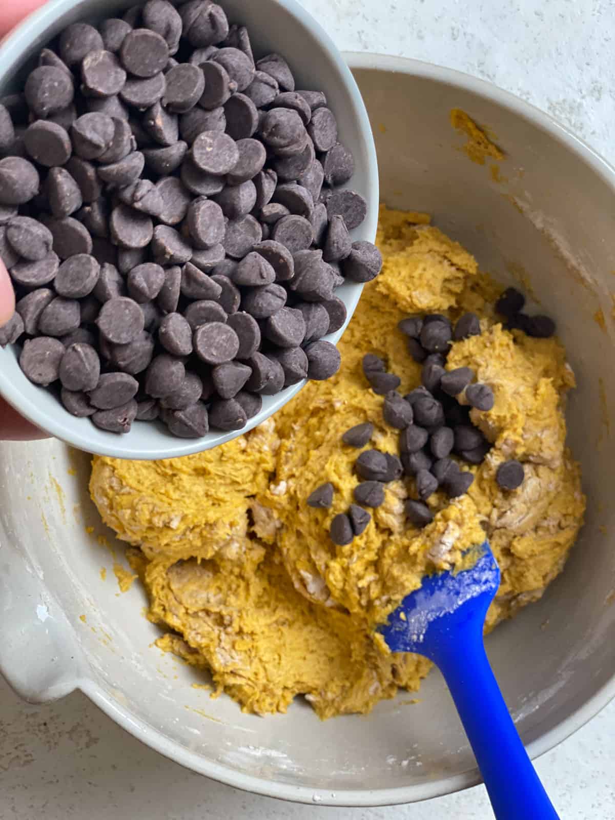 process of adding vegan chocolate chips to pumpkin mixture