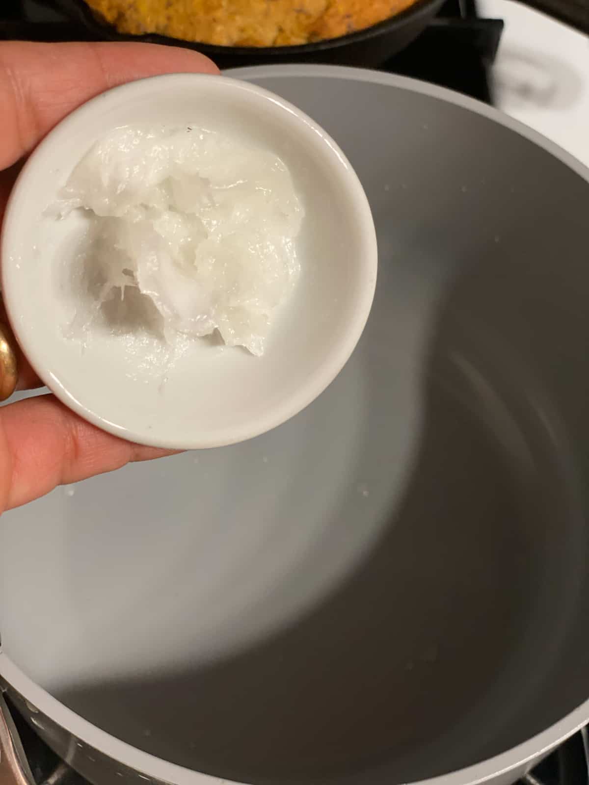 process shot of coconut oil being added to a pan