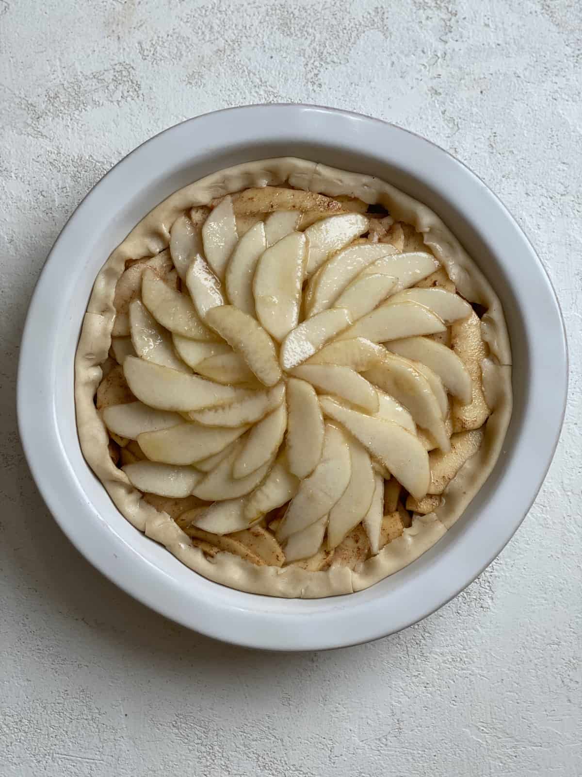 pre baked apple pear pie against a white surface