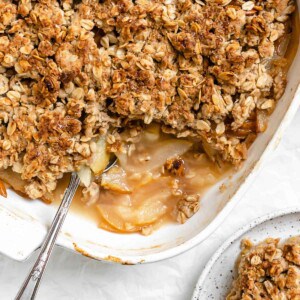 completed Easy Pear Crisp [Vegan Pear Crumble] in a baking tray alongside a plate of one piece of crisp