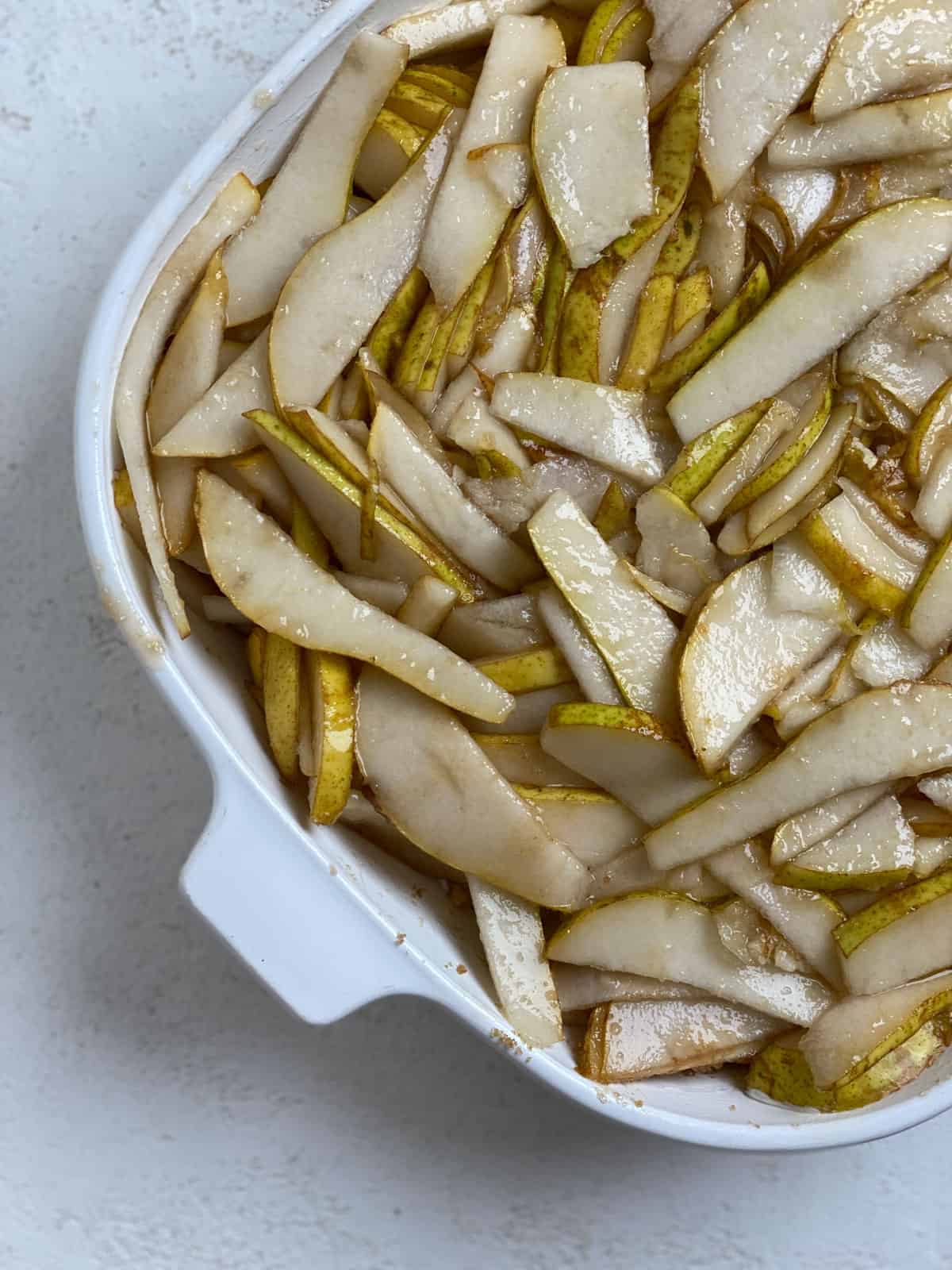 process shot showing sliced pears and brown sugar mixed together in baking dish