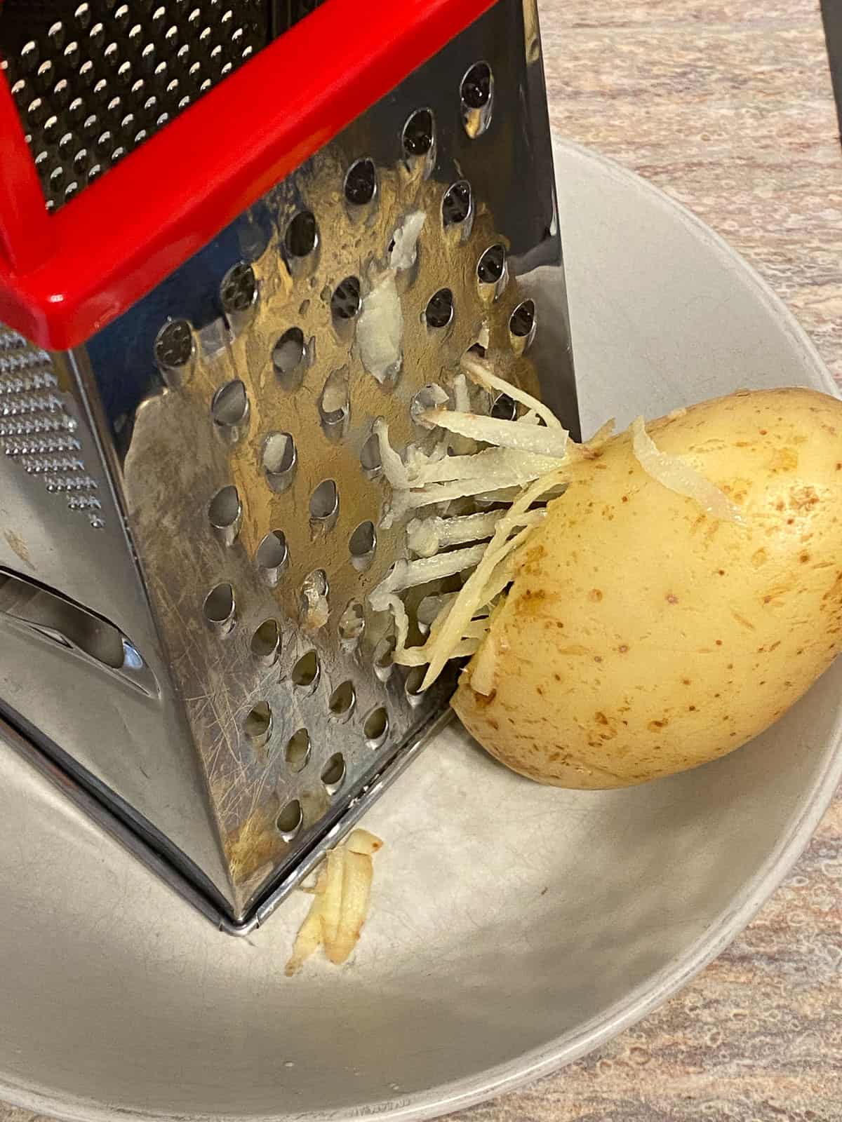 process shot of shredding potato with grater in bowl