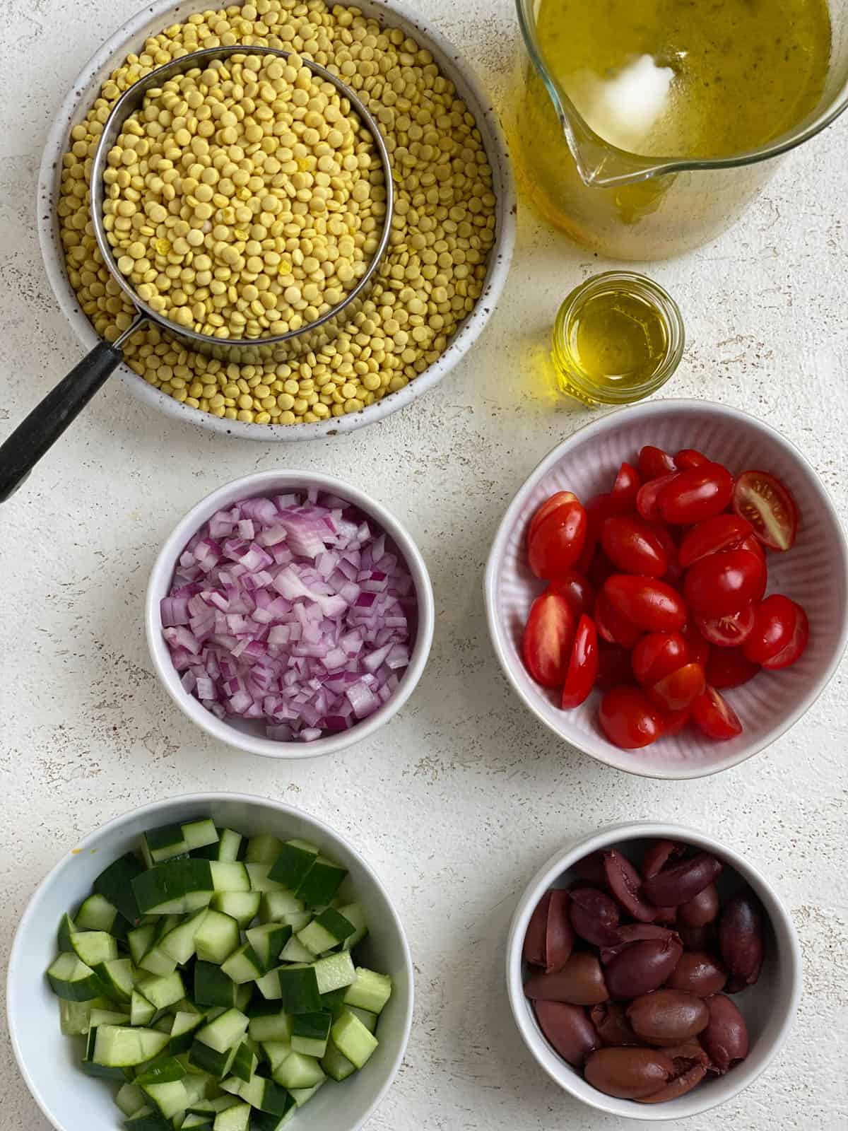ingredients for Mediterranean Pearl Couscous Salad measured out against a white surface