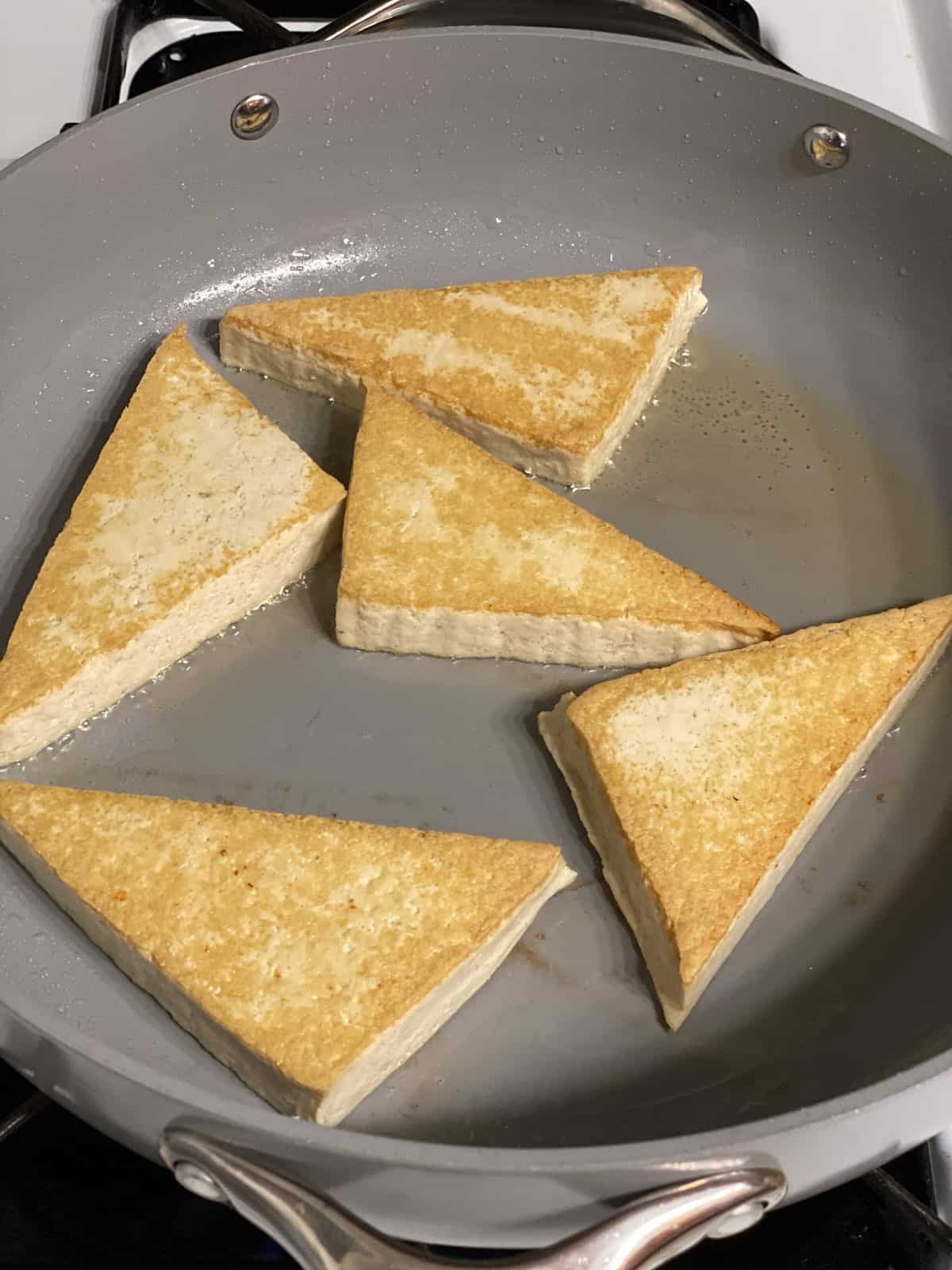 process shot of cooking tofu wedges on a pan