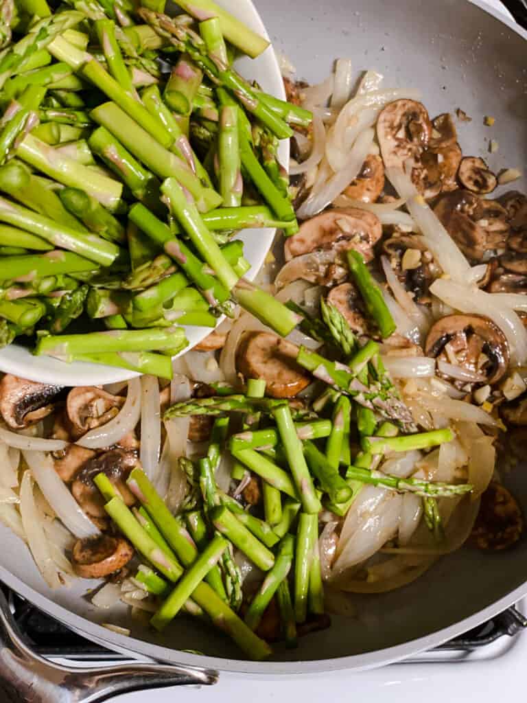 process s،t of asparagus being added to pan