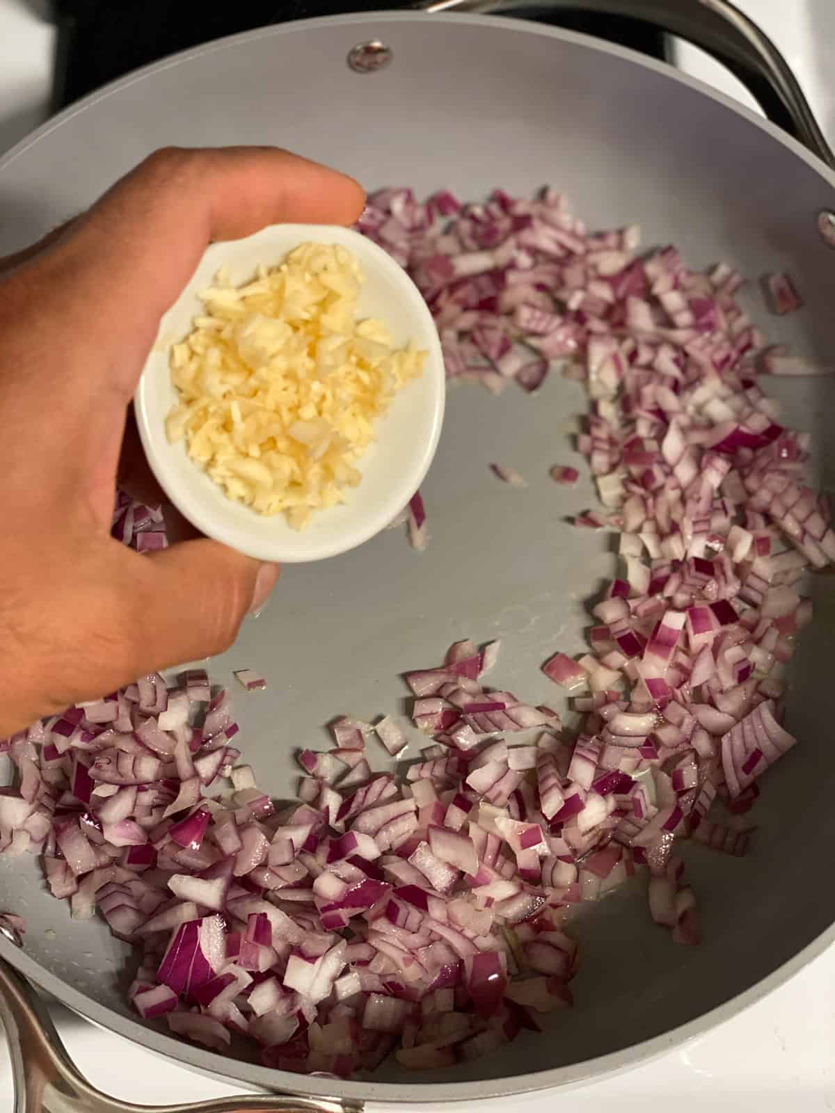 process shot of adding garlic to pan