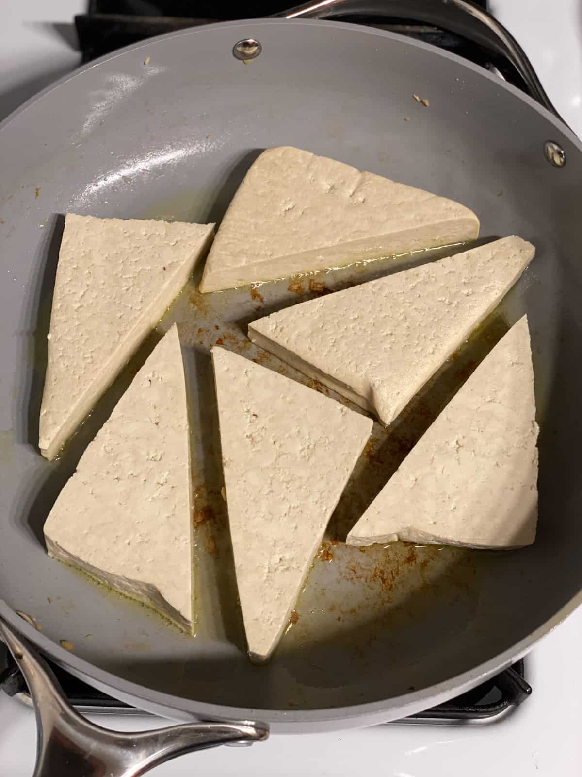 process of adding triangular tofu in pan