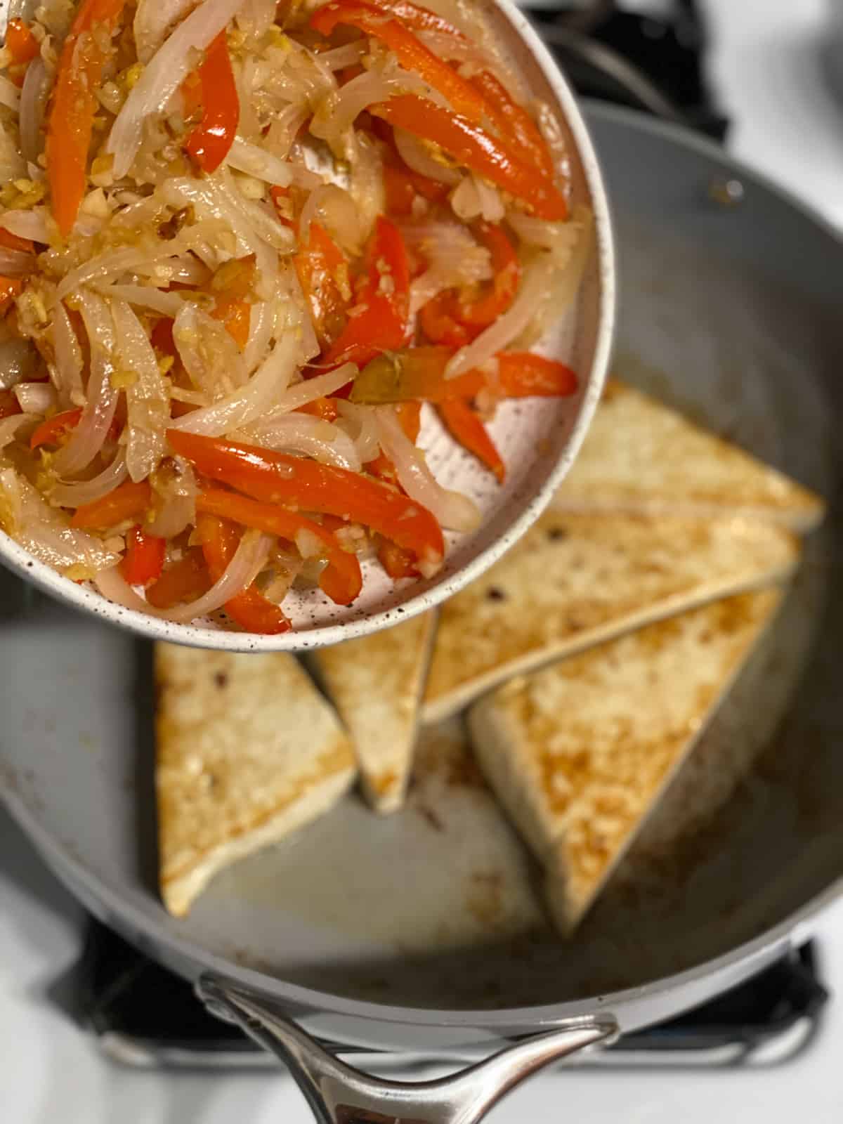 process of adding veggies on top of tofu in pan