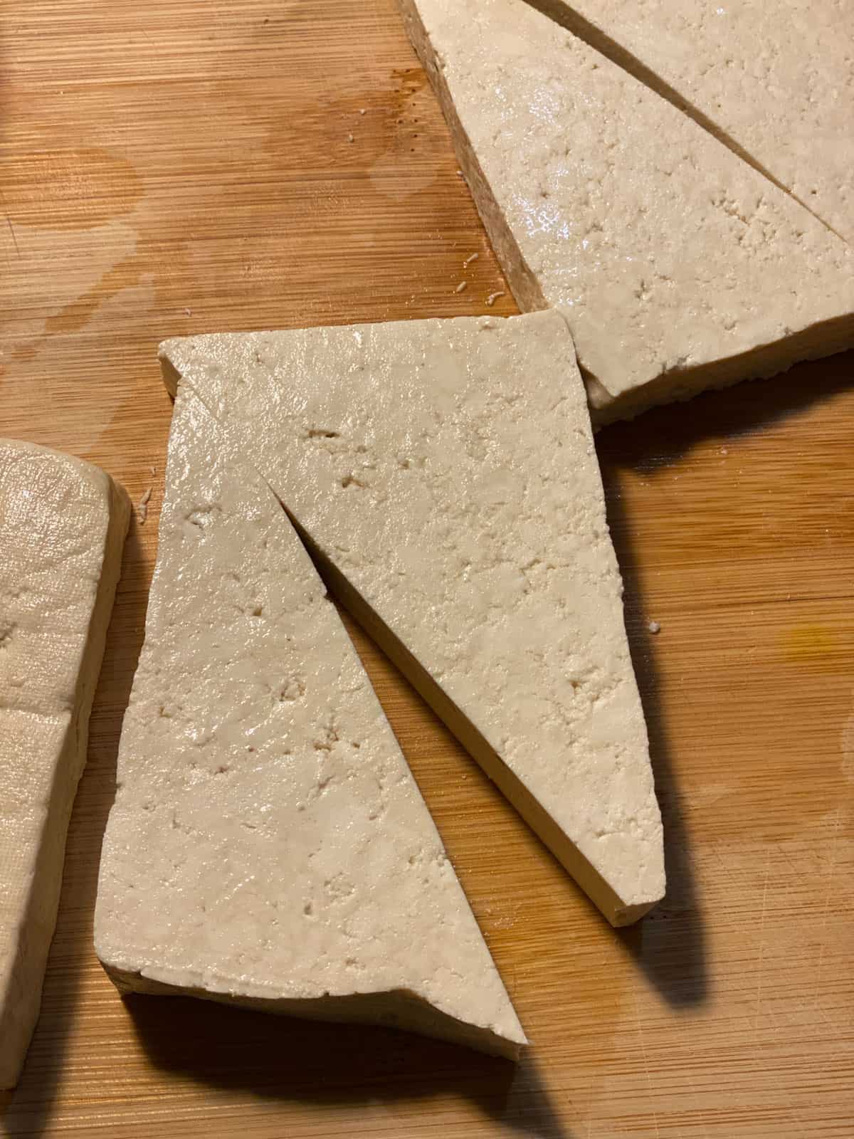 process of showing triangular cut of tofu on cutting block