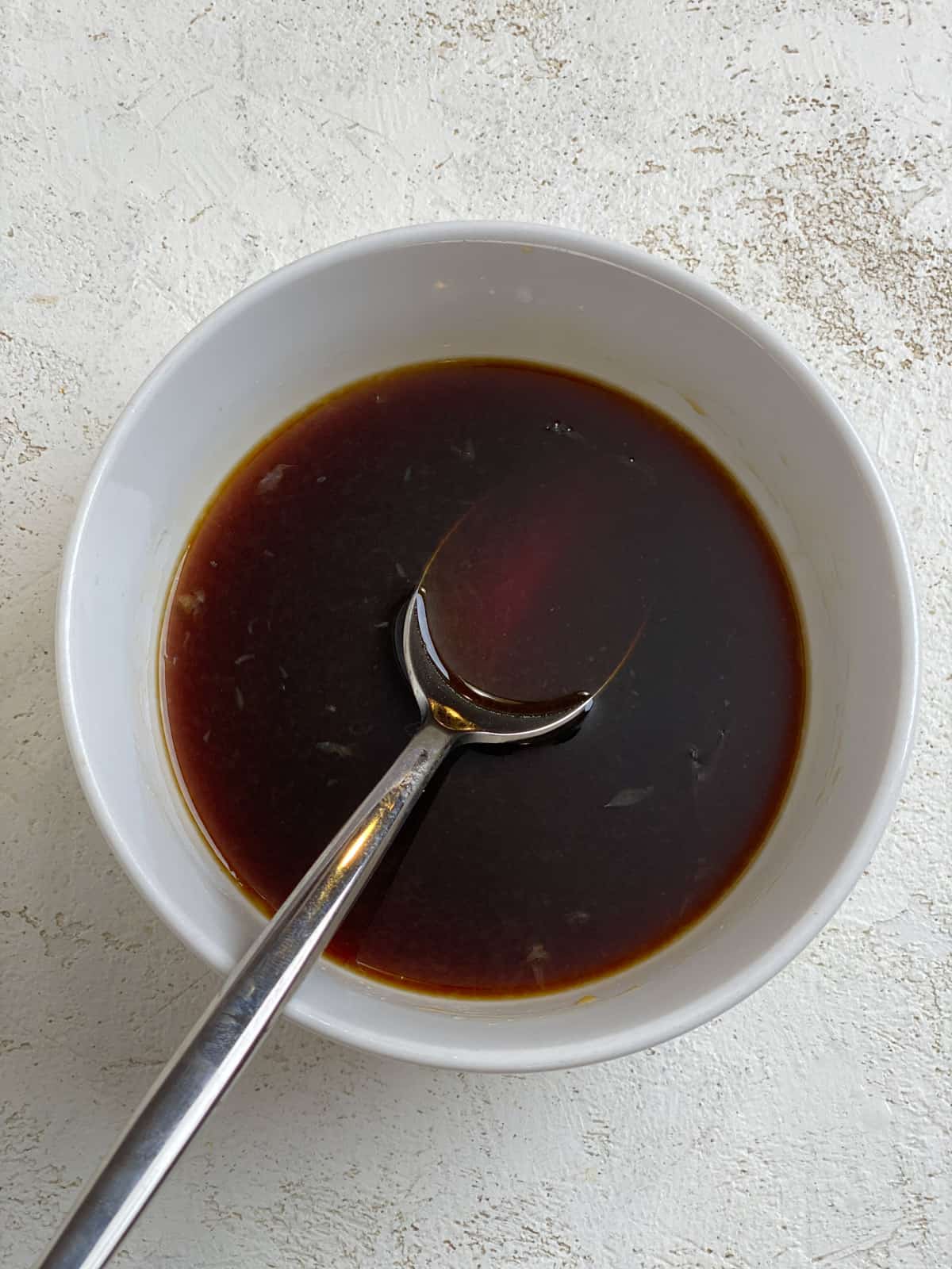process of mixing soy sauce mixture in small white bowl