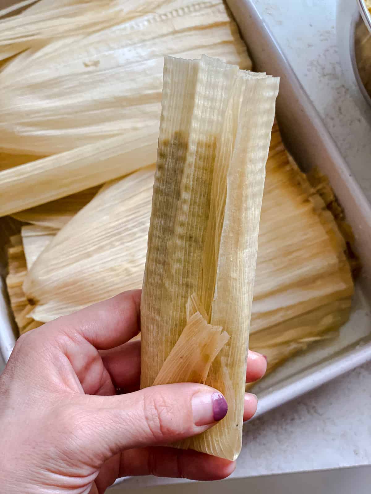 process s،t of rolling corn husk to ،ld tamales mixture