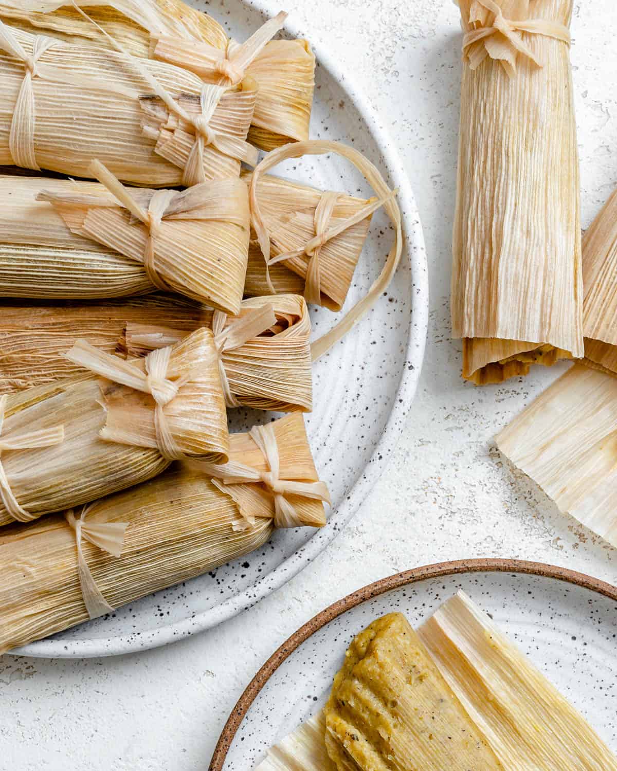 several completed tamales on a plate and on top of a white surface
