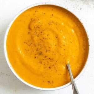 completed Creamy Curried Carrot Ginger Soup in a white bowl against a white background