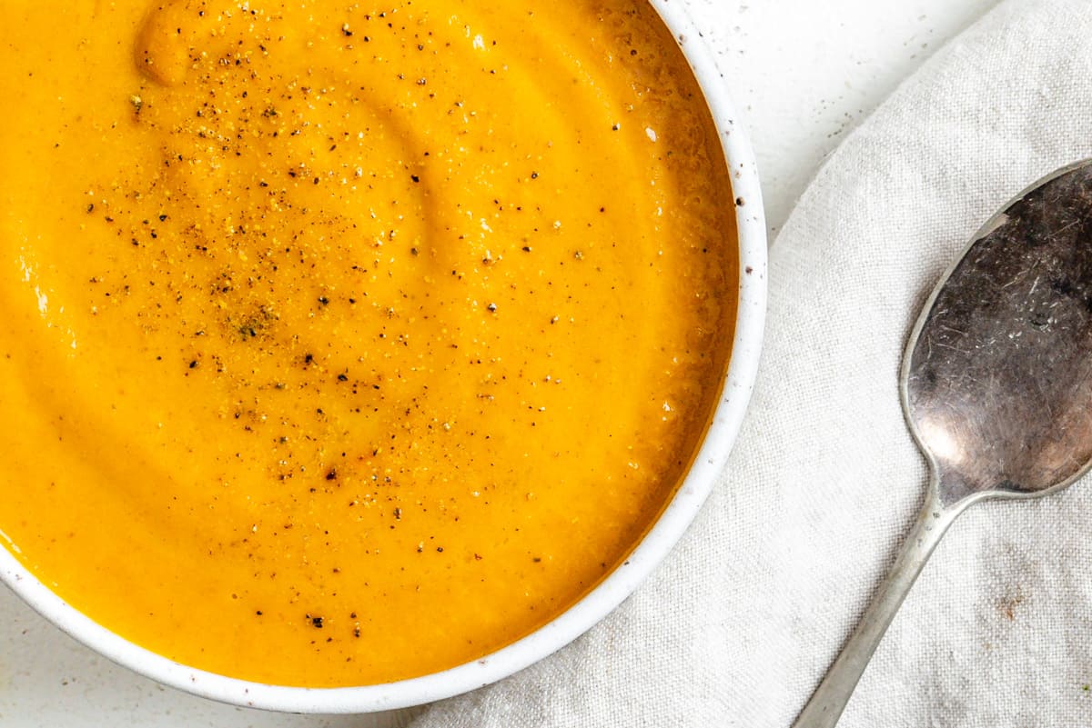completed Creamy Curried Carrot Ginger Soup in a white bowl against a white background