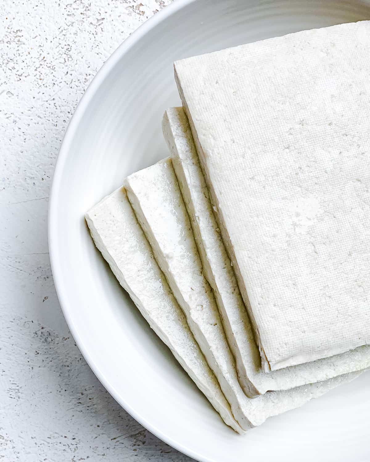 sliced ​​tofu on a white plate against a white background