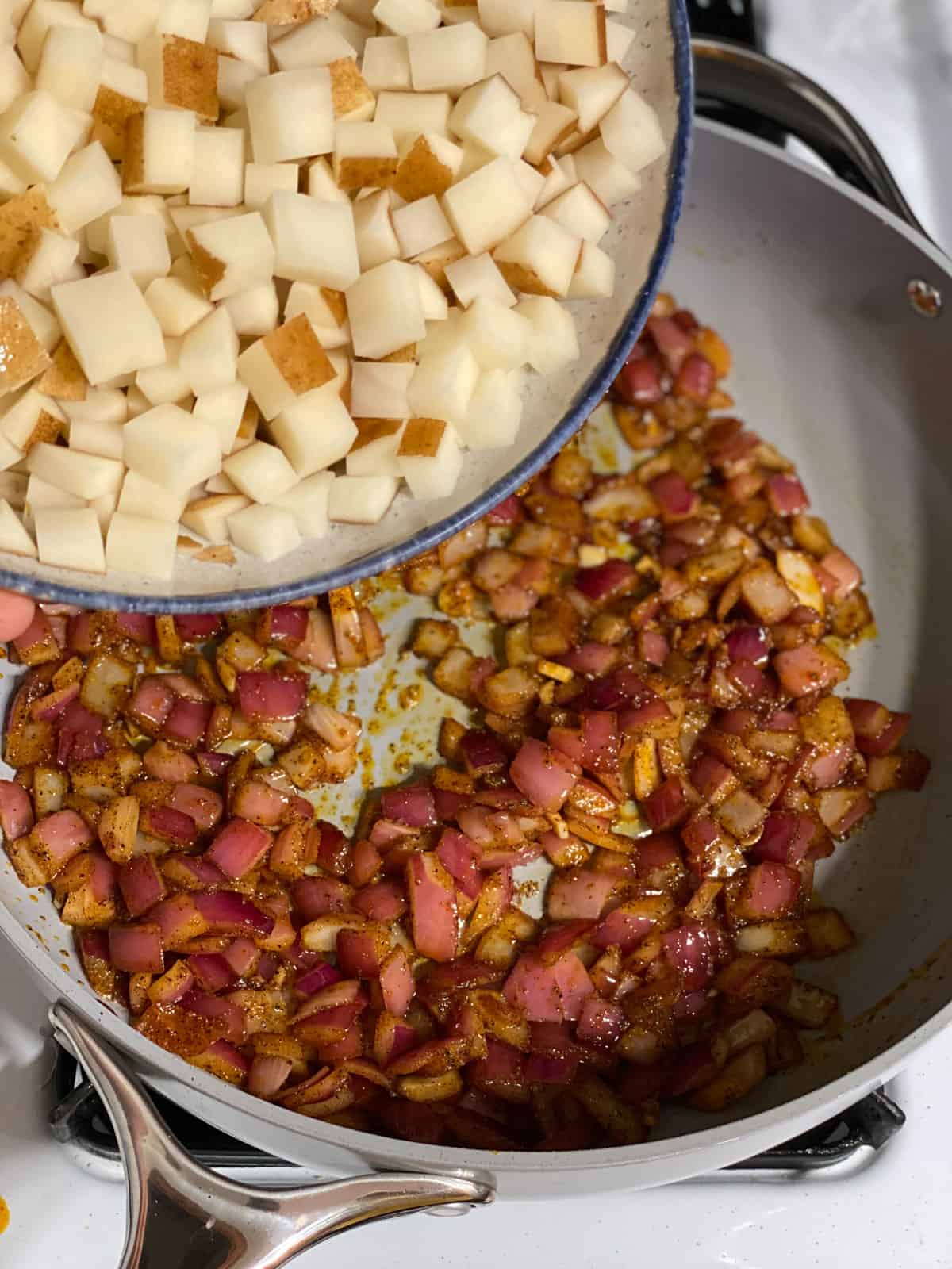 process shot of adding potatoes to pan