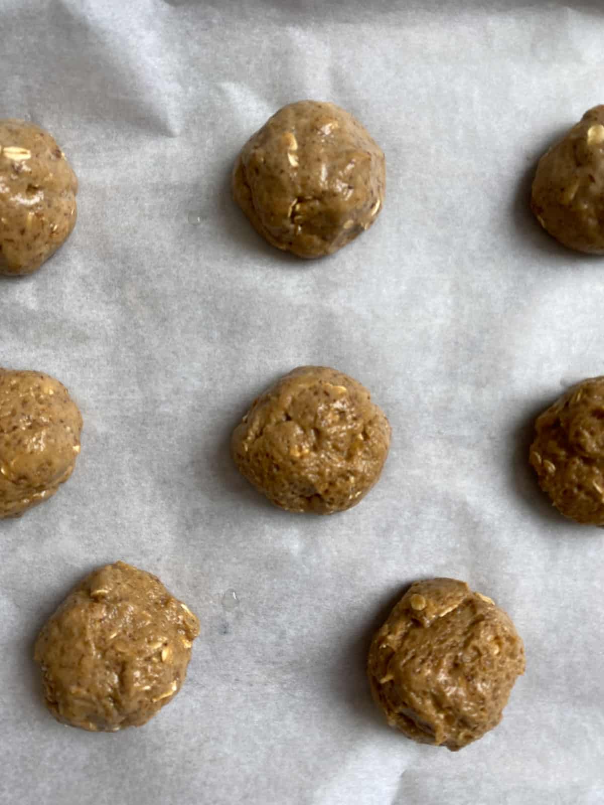process shot of several peanut butter balls rolled out onto parchment paper
