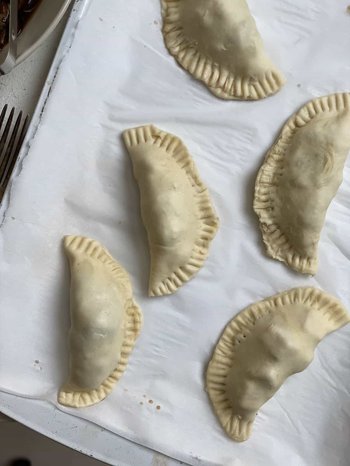 several unbaked Spinach and Mushroom Puffs [Vegan Hand Pies] on a baking dish