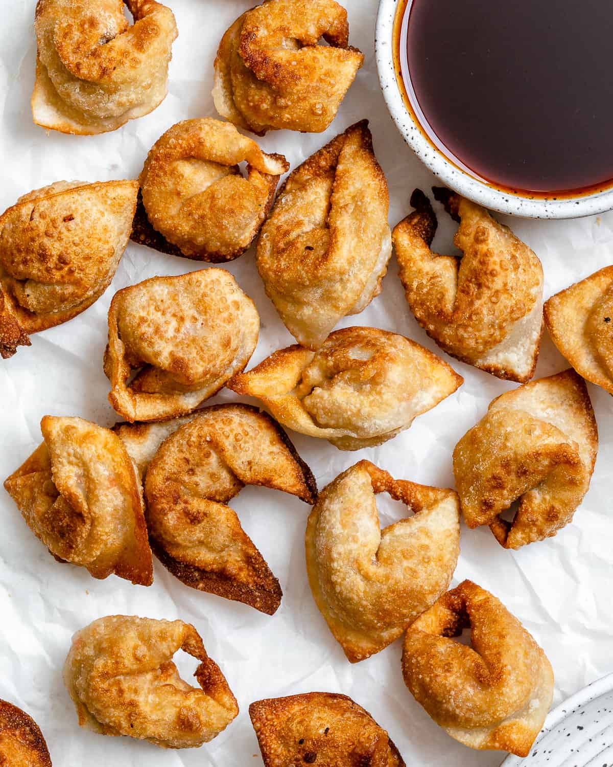 several completed Tofu Vegetable Crispy Wontons spread out on a white surface