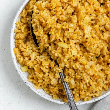 completed Garlic Rice [Spanish Yellow Rice] in a white bowl against a white background