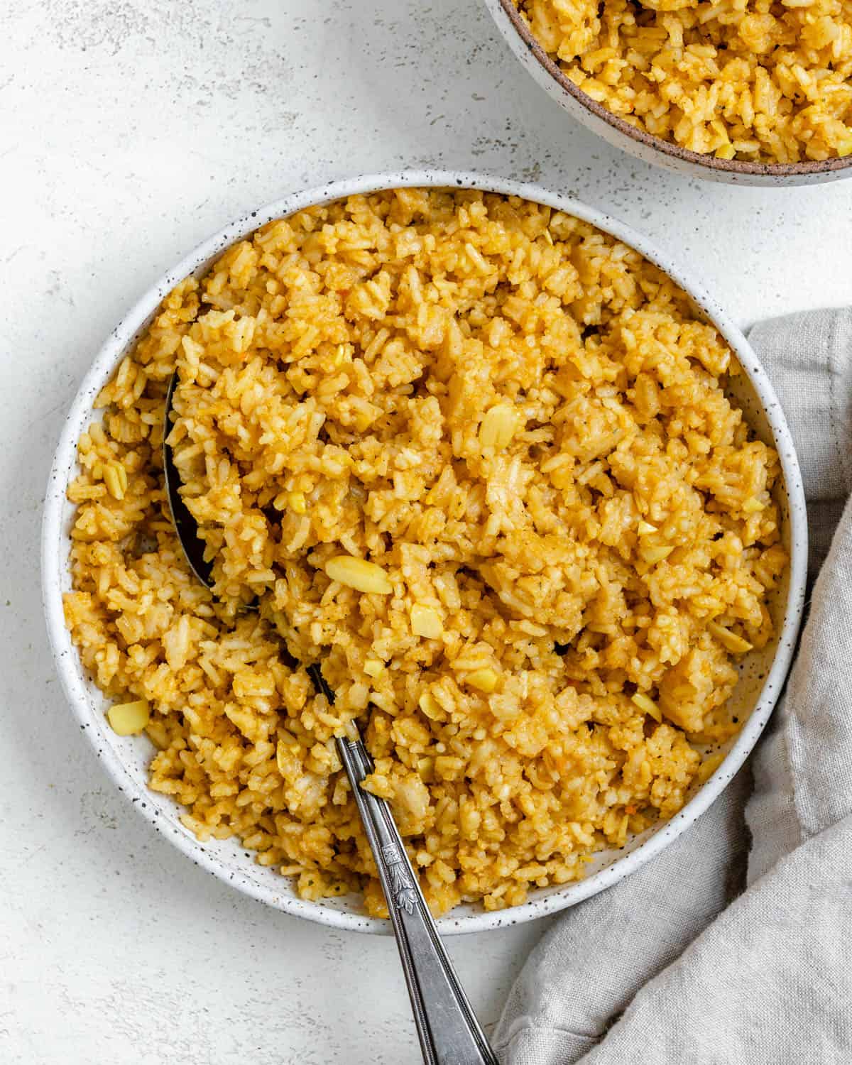 completed Garlic Rice [Spanish Yellow Rice] in a white bowl against a white background
