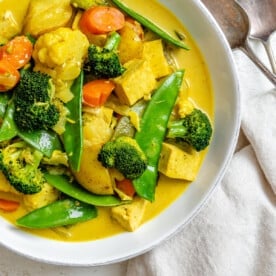 abgeschlossenes einfaches Tofu-Gemüse-Kokos-Curry in einer Schüssel gegen einen weißen Hintergrund