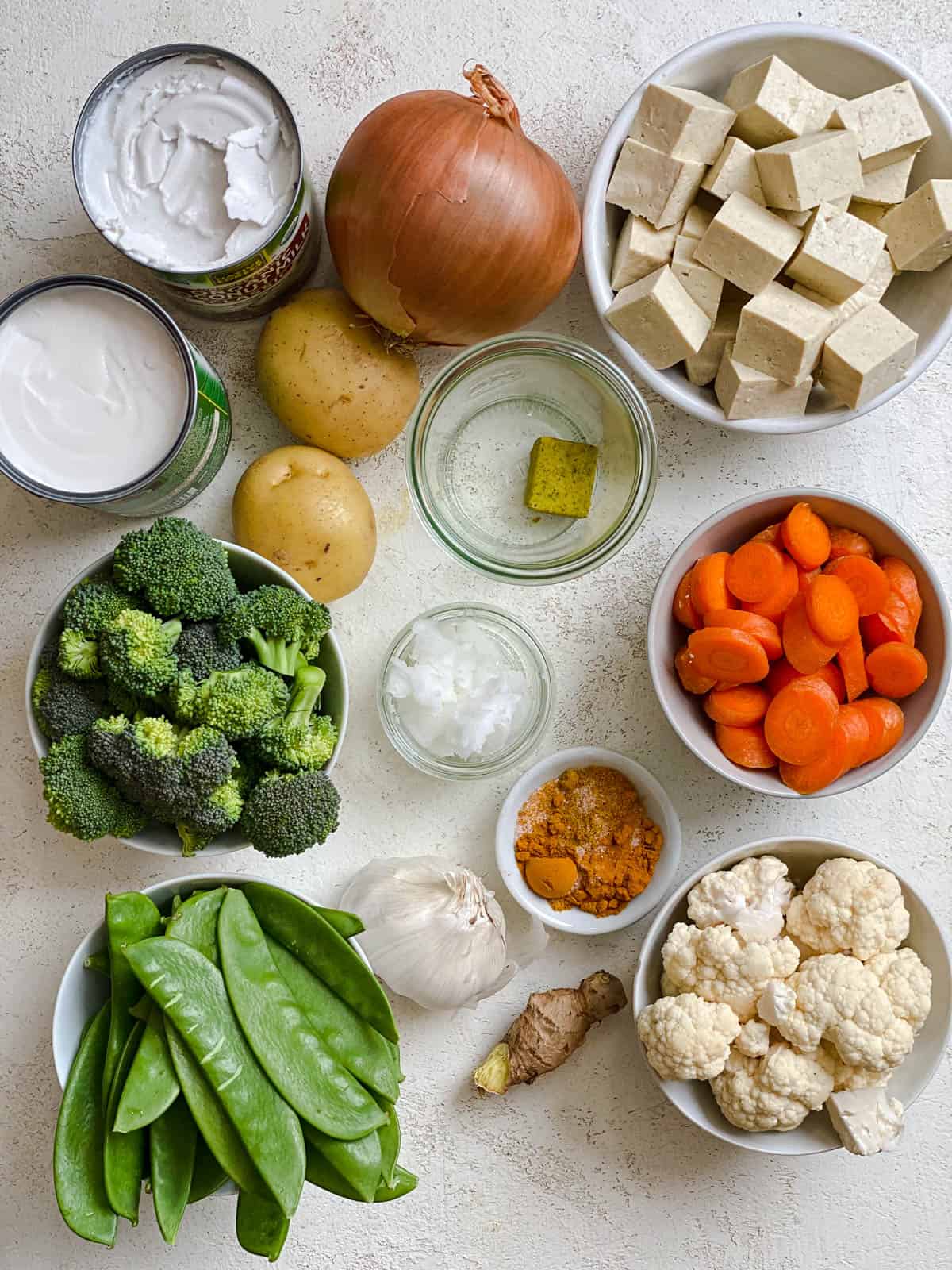 Zutaten für einfaches Tofu-Gemüse-Kokos-Curry, gemessen auf einer weißen Fläche
