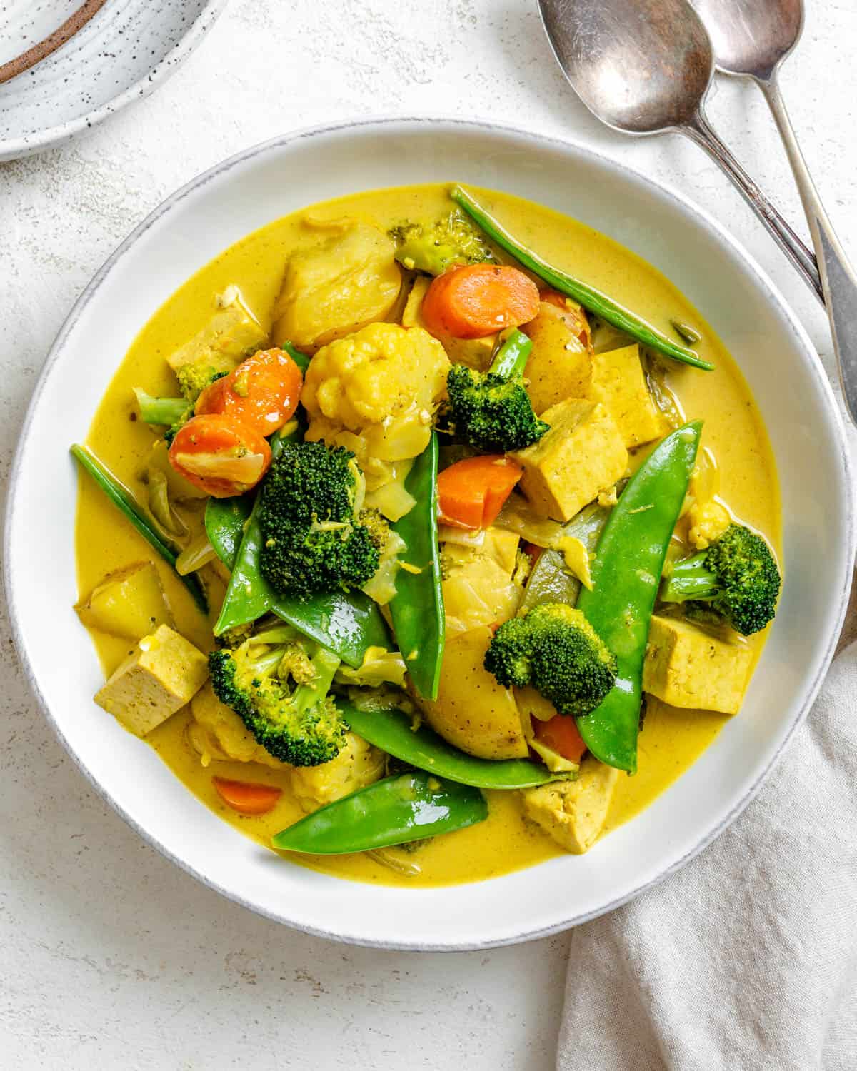 abgeschlossenes einfaches Tofu-Gemüse-Kokos-Curry in einer Schüssel gegen einen weißen Hintergrund