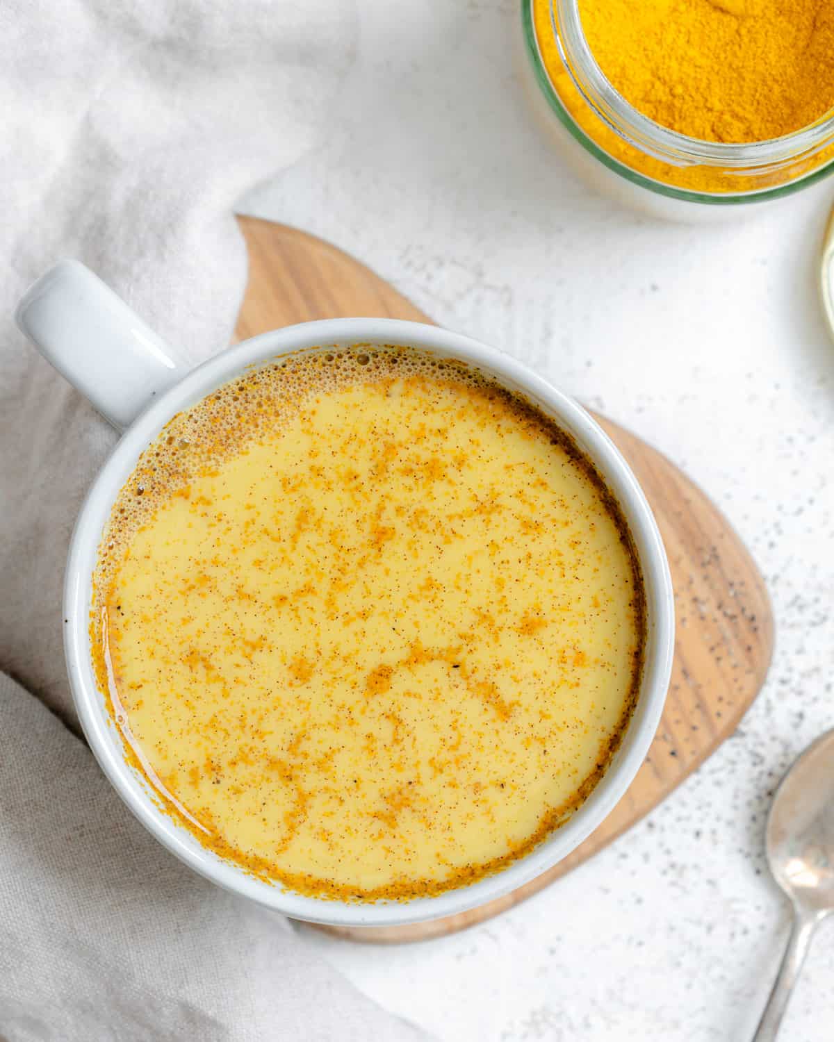 completed Turmeric Golden Milk [Haldi Doodh] in a white cup against a white background