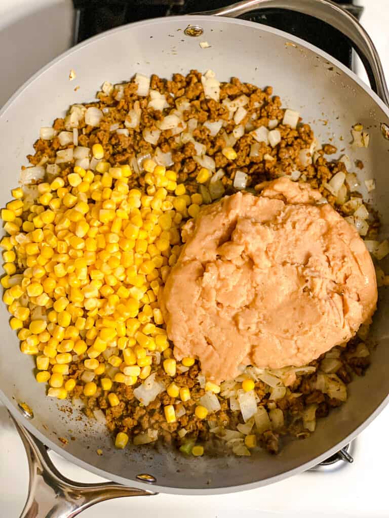process shot of beans and corn being added to pan