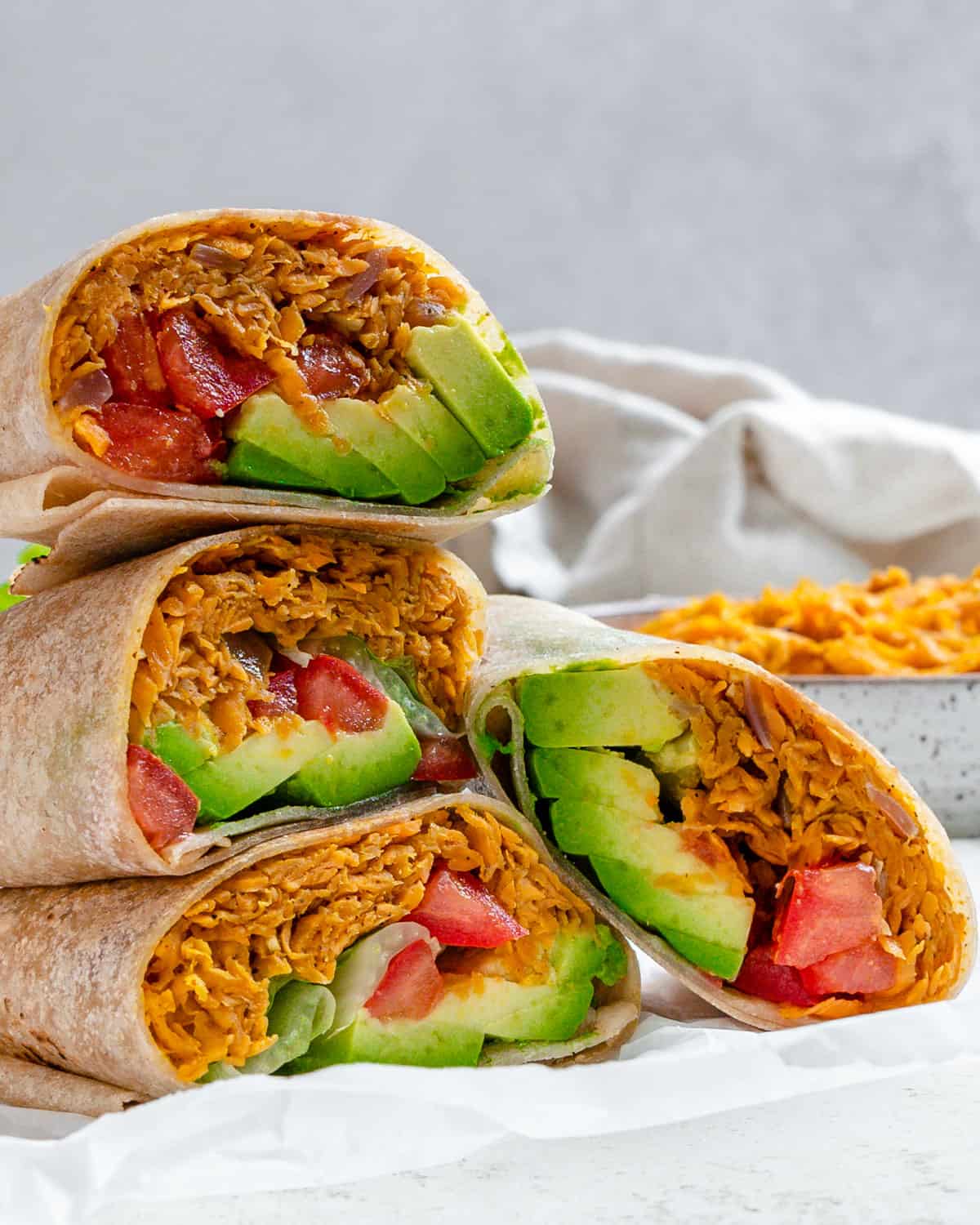 completed Sweet Potato Burritos stacked on one another against a light background