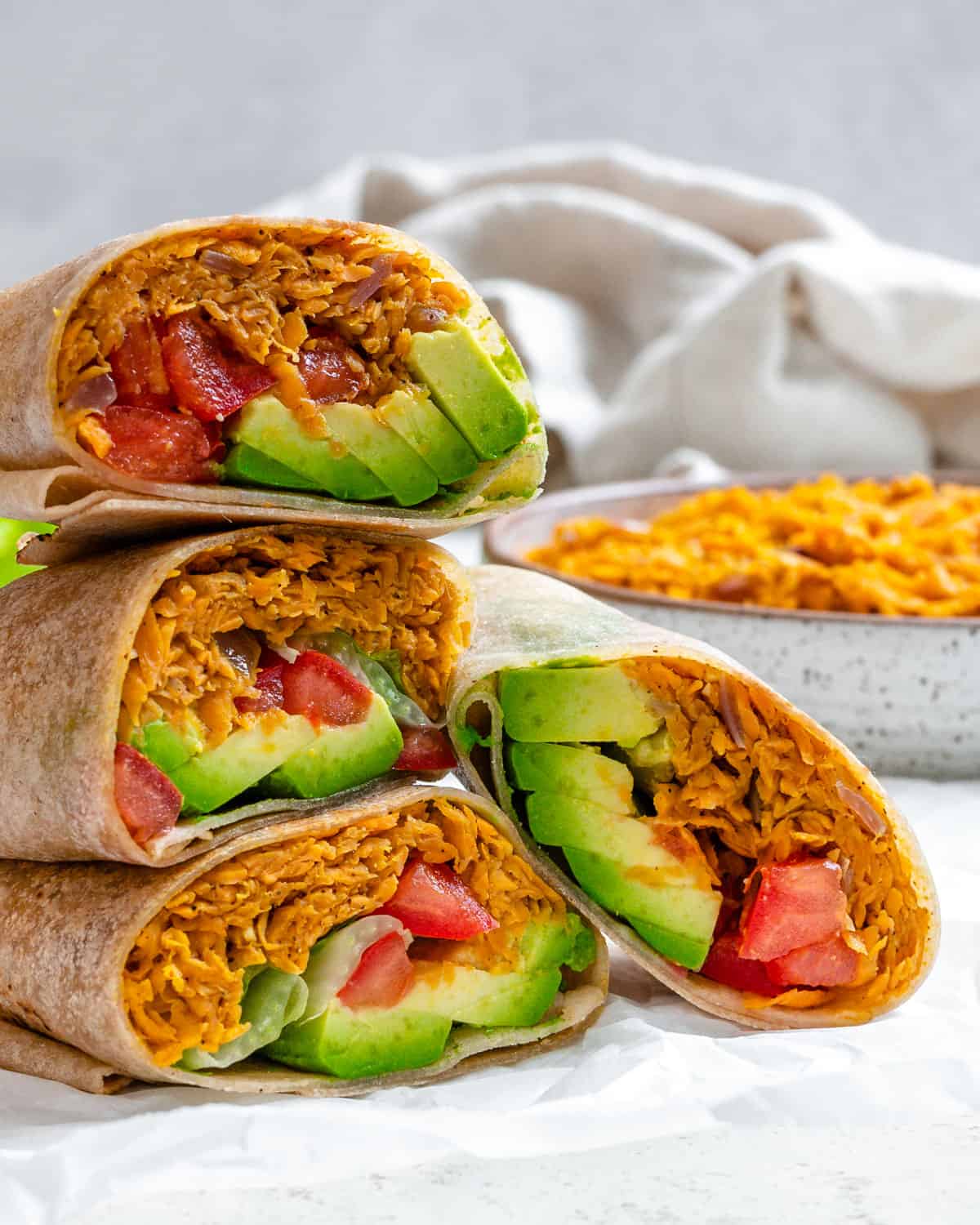 completed Sweet Potato Burritos stacked on one another against a light background