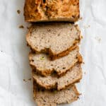 completed sliced Easy Vegan Banana Bread (With Applesauce) in a loaf pan against a white background