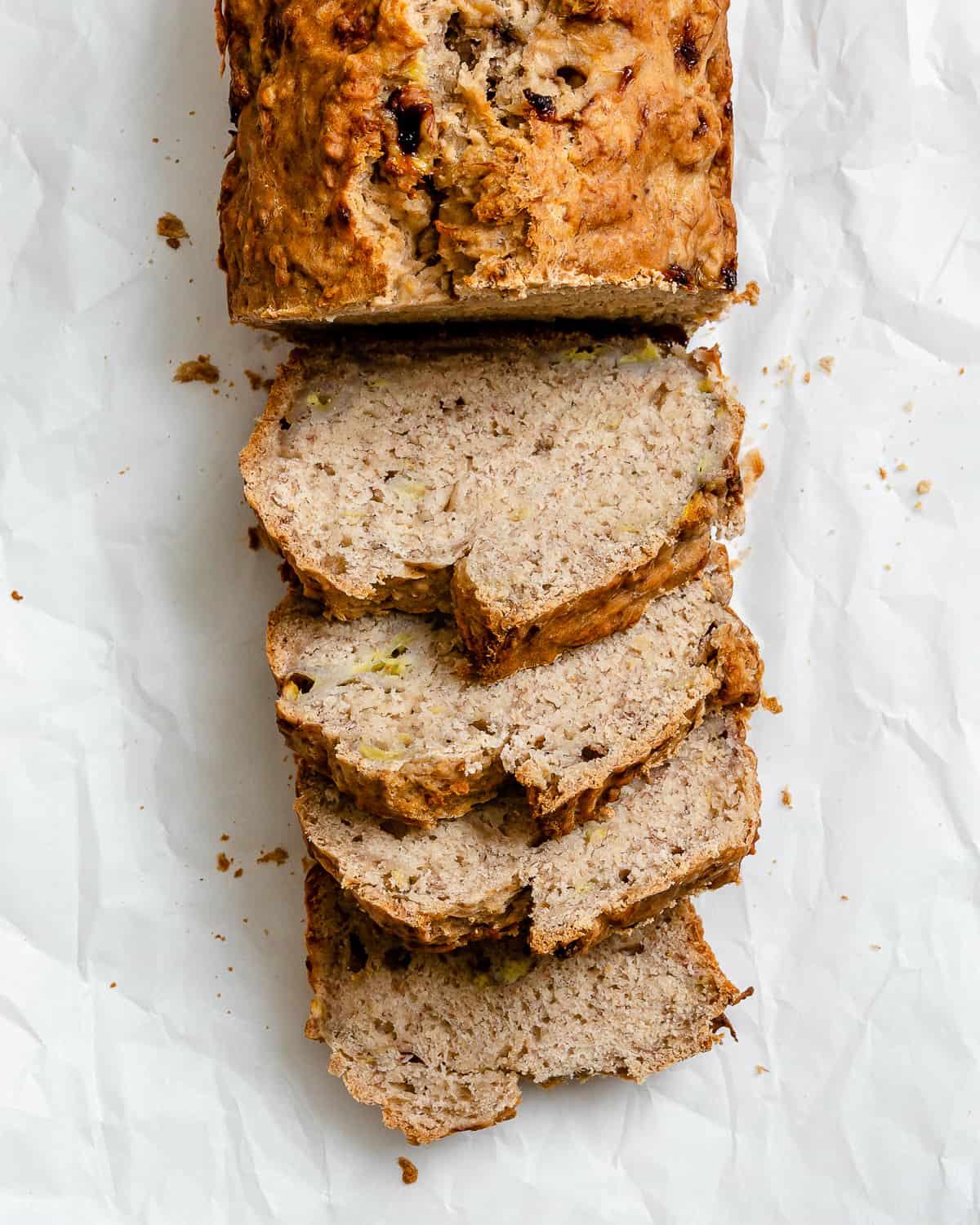 completed sliced Easy Vegan Banana Bread (With Applesauce) in a loaf pan against a white background