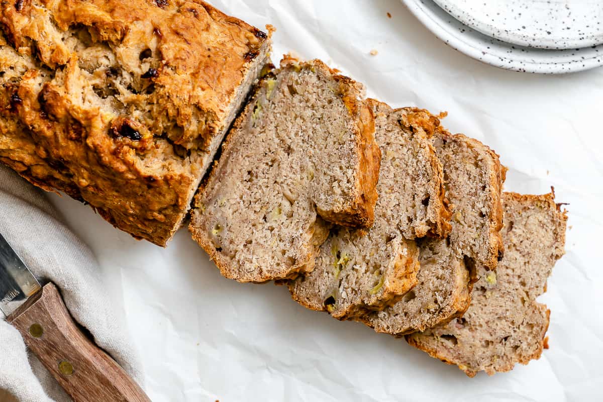 completed sliced Easy Vegan Banana Bread (With Applesauce) in a loaf pan against a white background