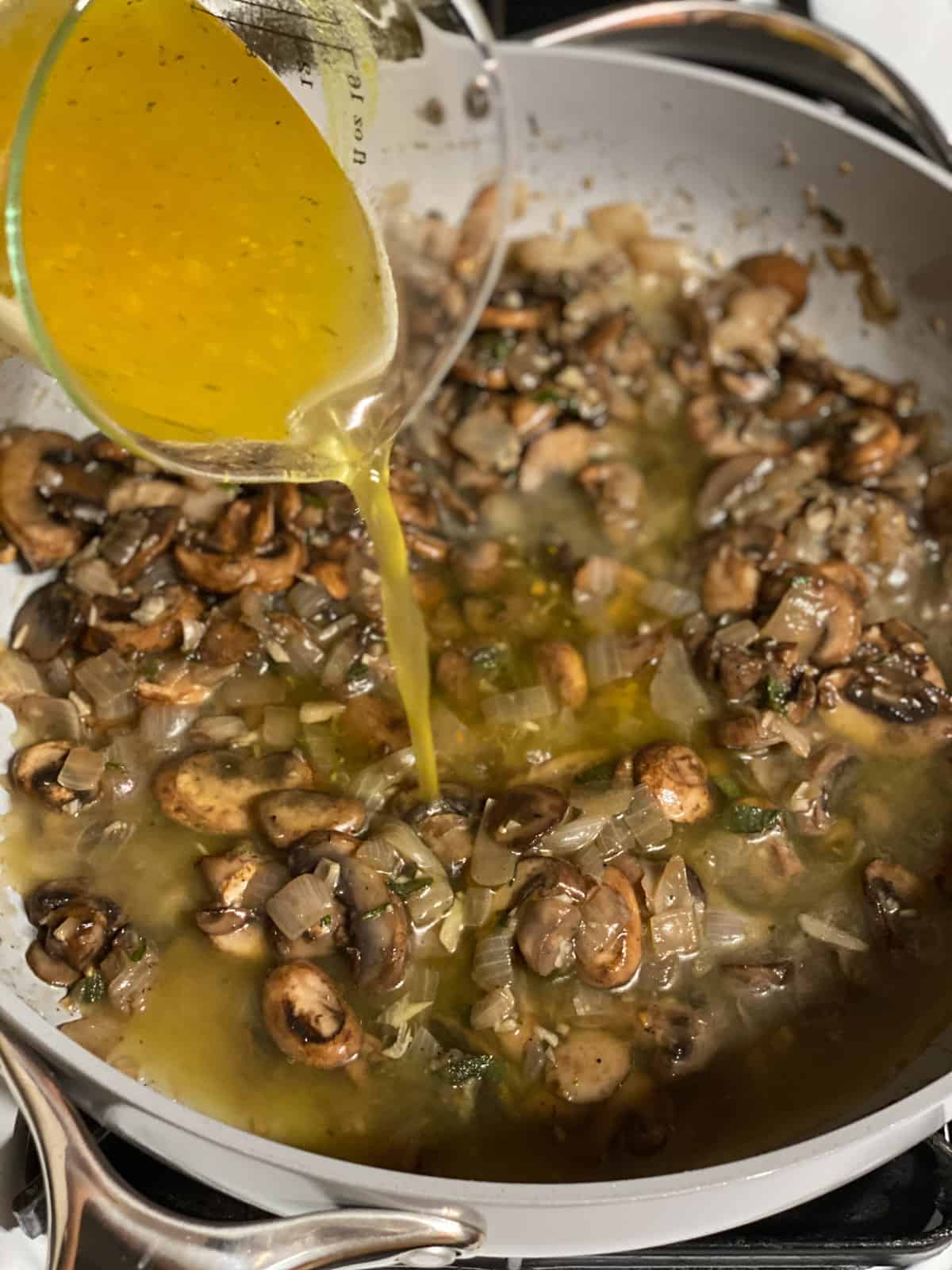 Vegetable broth being poured into the mushrooms for vegan mushroom gravy.