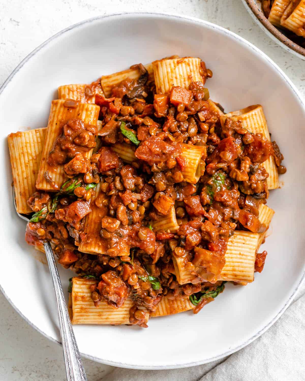 completed Vegan Lentil Bolognese plated on a white plate against a white background