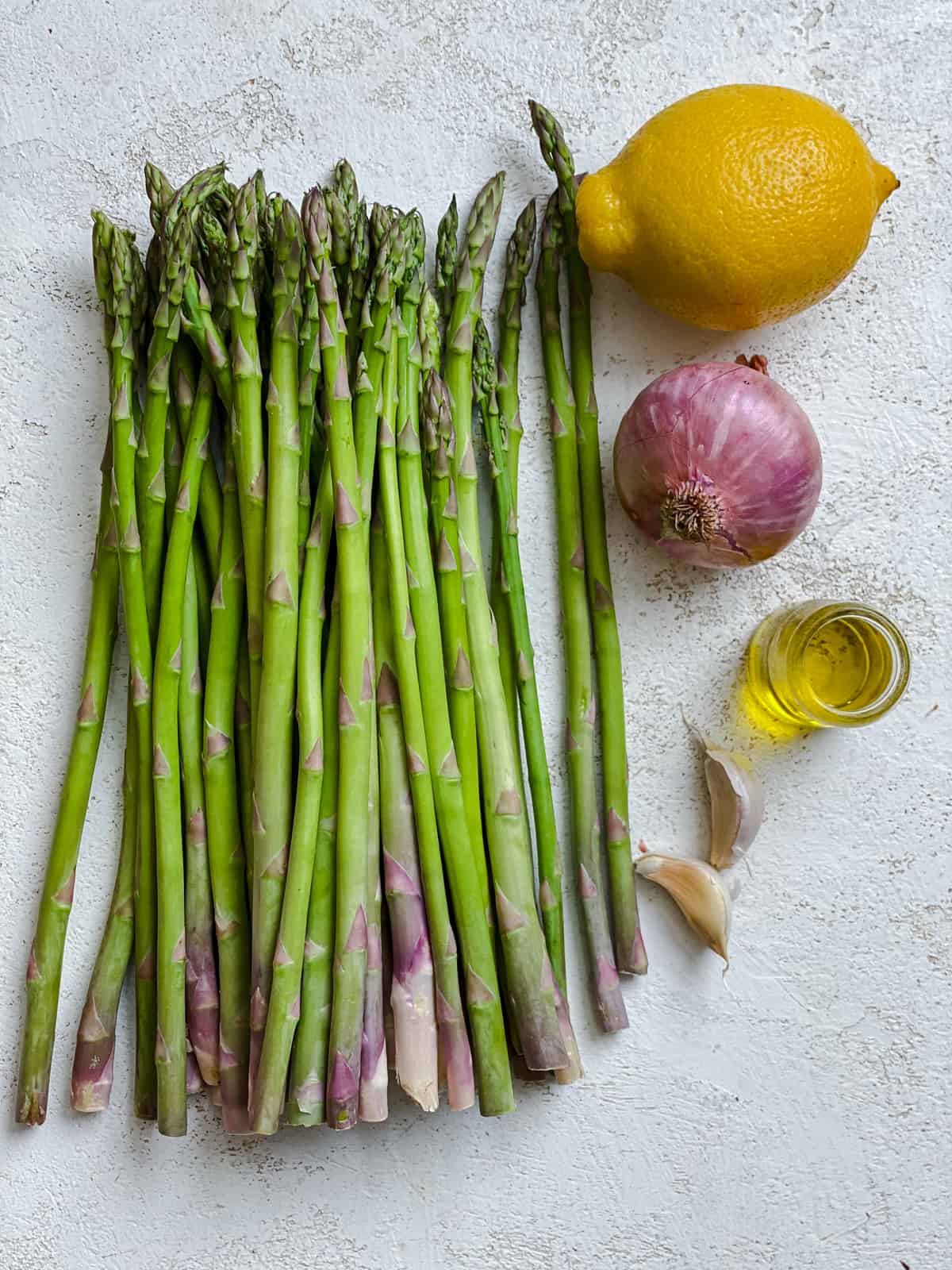 ingredients for Sauteed Asparagus with Lemon and Garlic measured out against a white surface