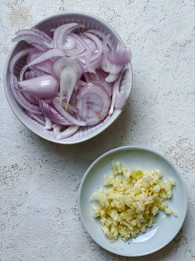 sliced onions and minced garlic in individual bowls