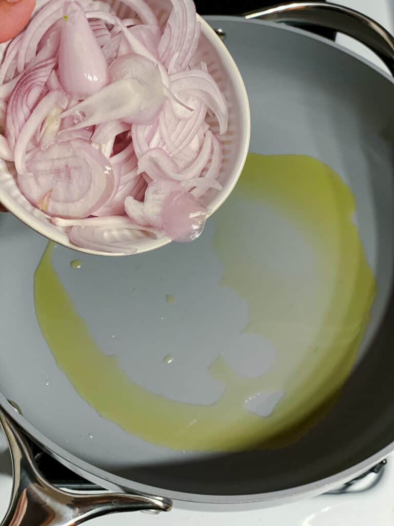 Process shot of adding onions to the pan