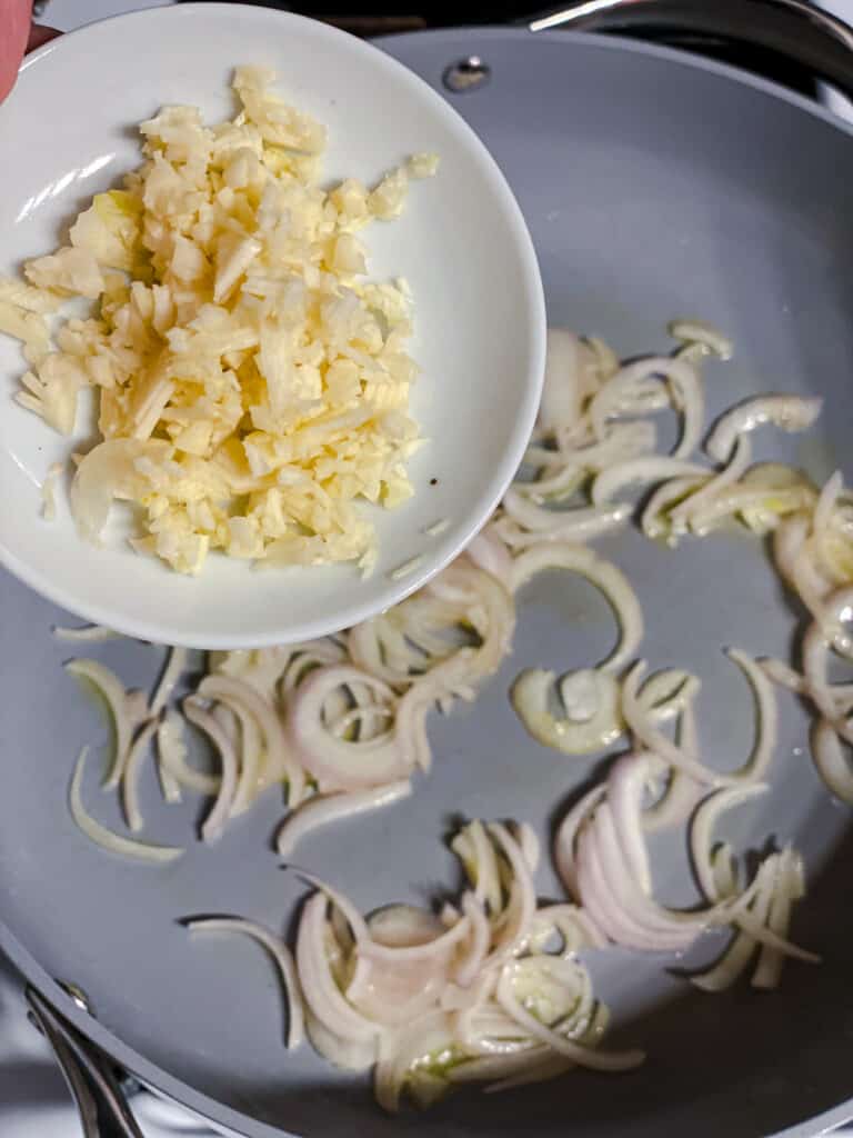 Process shot of adding garlic to the pan