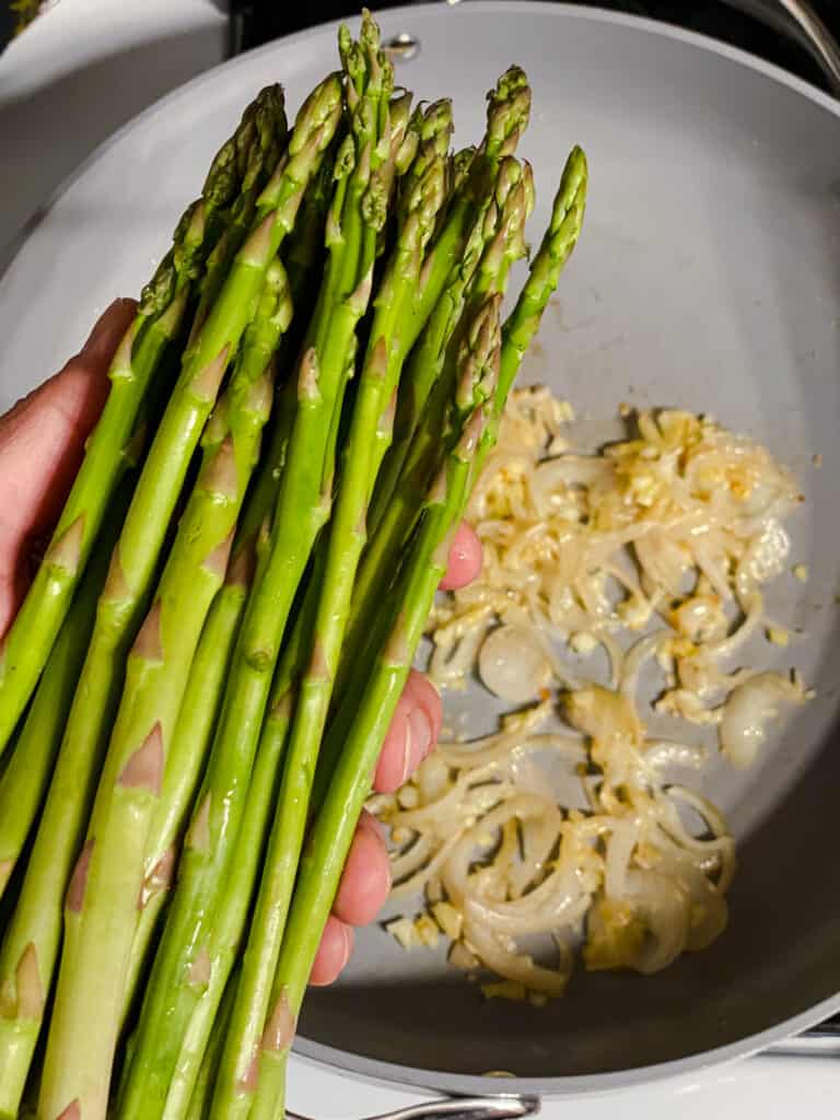 Process shot of adding asparagus to the pan