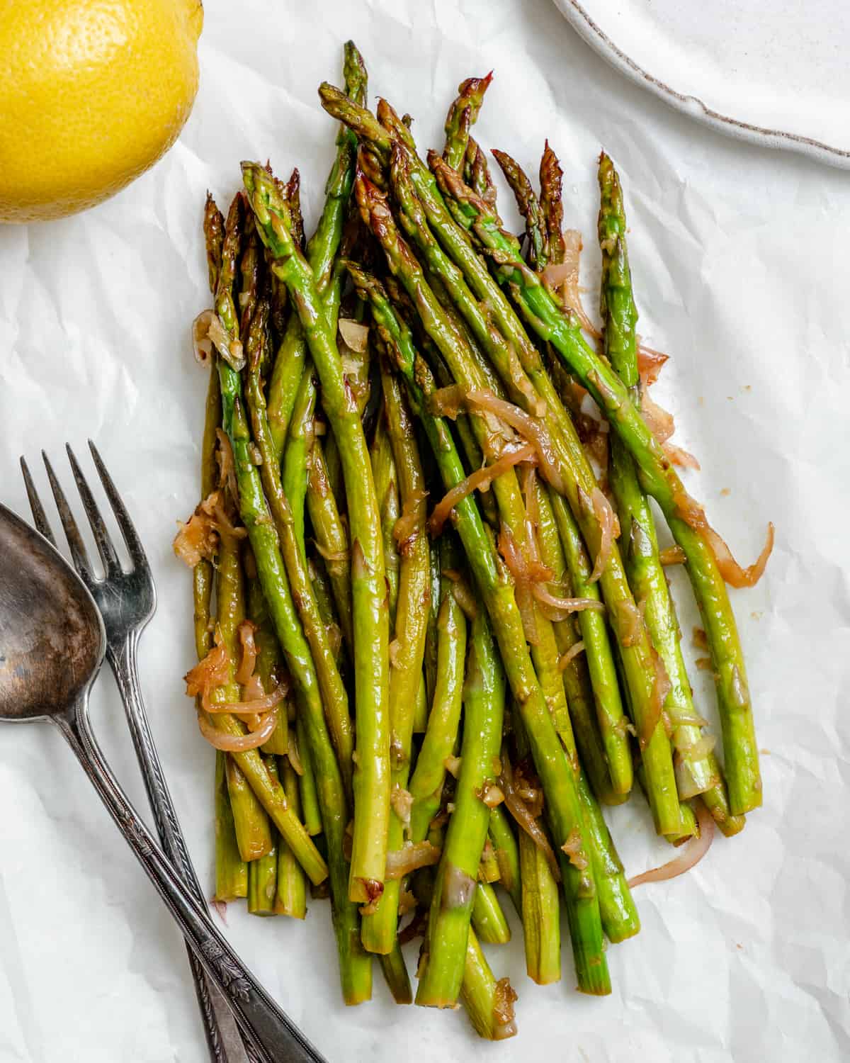 Ready sautéed asparagus with lemon and garlic against a white background 