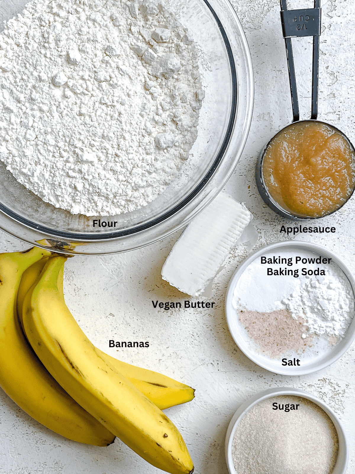 ingredients for Easy Vegan Banana Bread (With Applesauce) measured out on a white surface