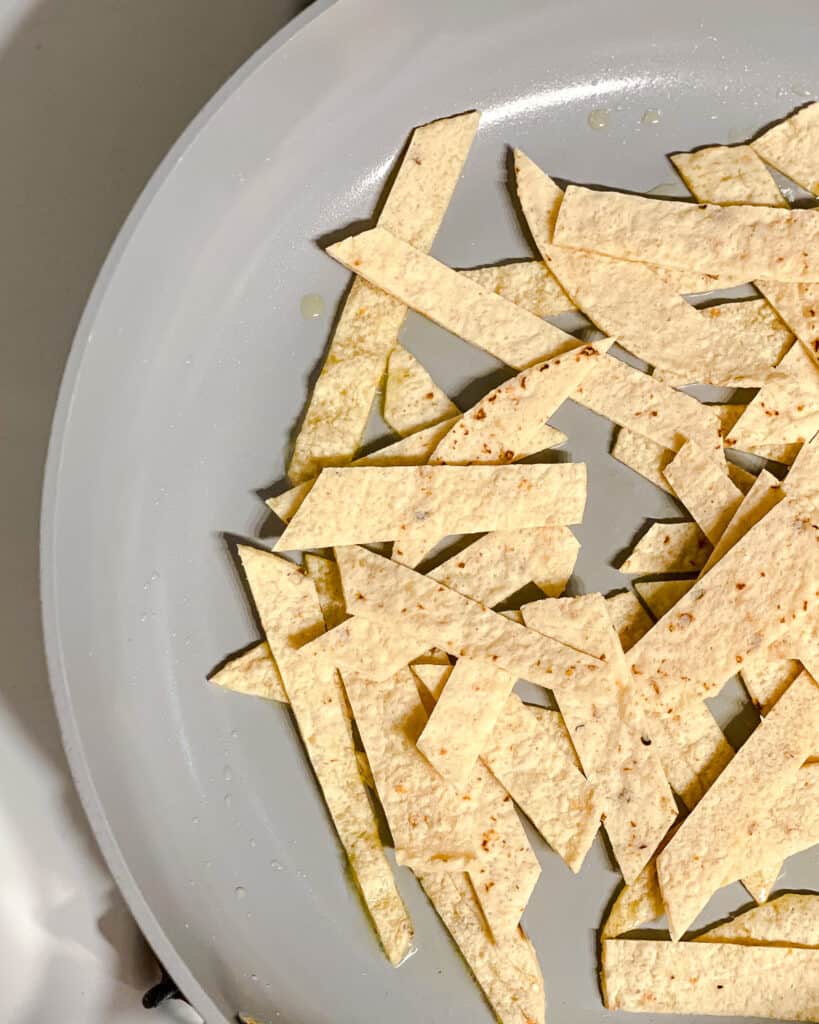 process shot of tortilla strips added to pan