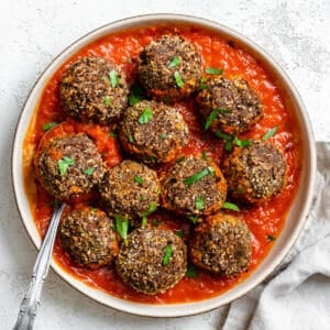 completed Easy Black Bean Meatballs spread out on plate or marinara against a white background