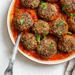 completed Easy Black Bean Meatballs spread out on plate or marinara against a white background